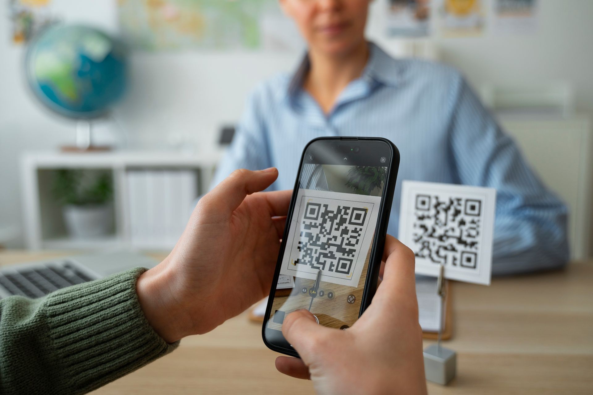 Person scanning a QR code with a smartphone in a modern office setting.